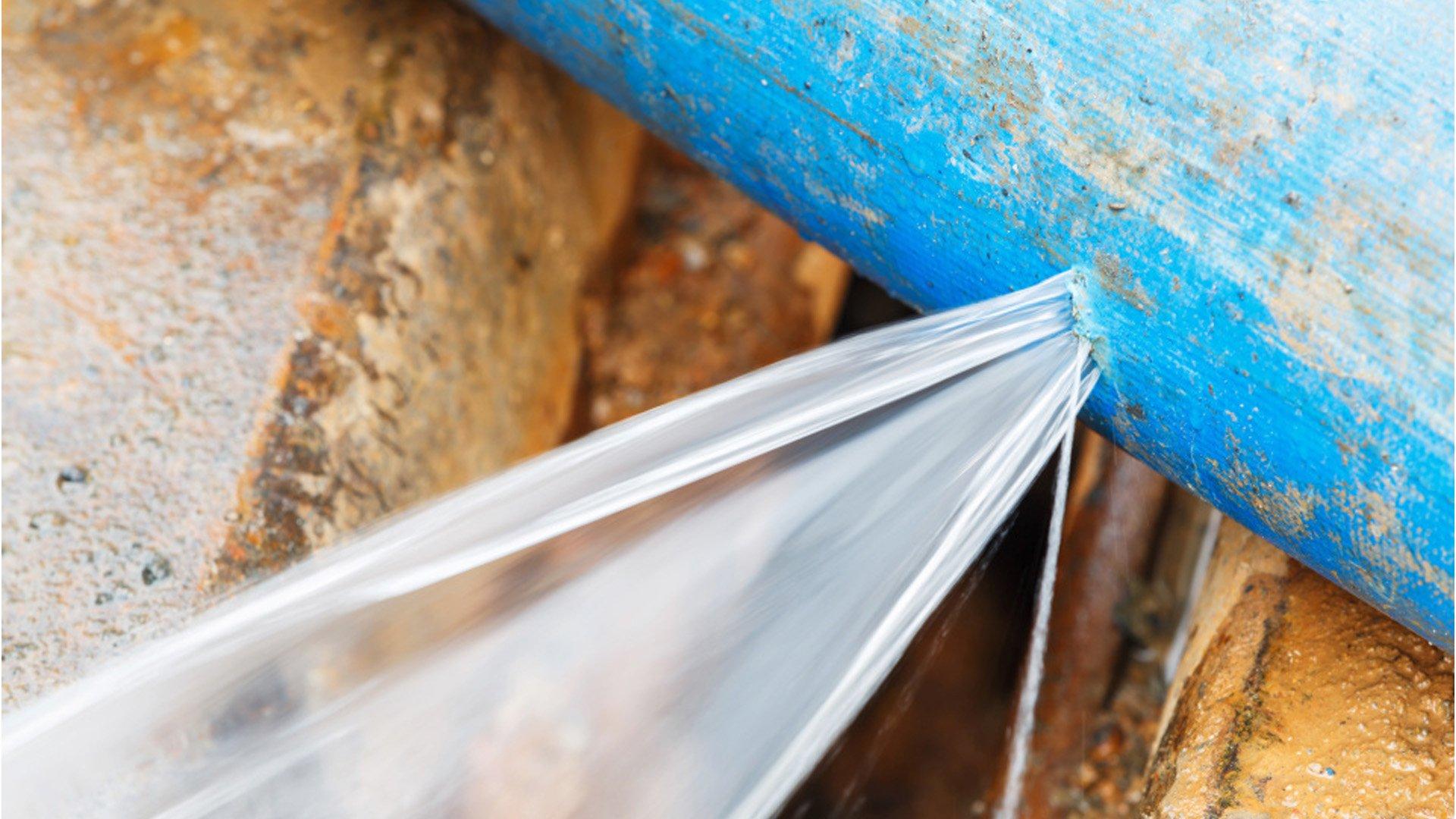 Pressurized water flows from a leak in a blue water pipe.